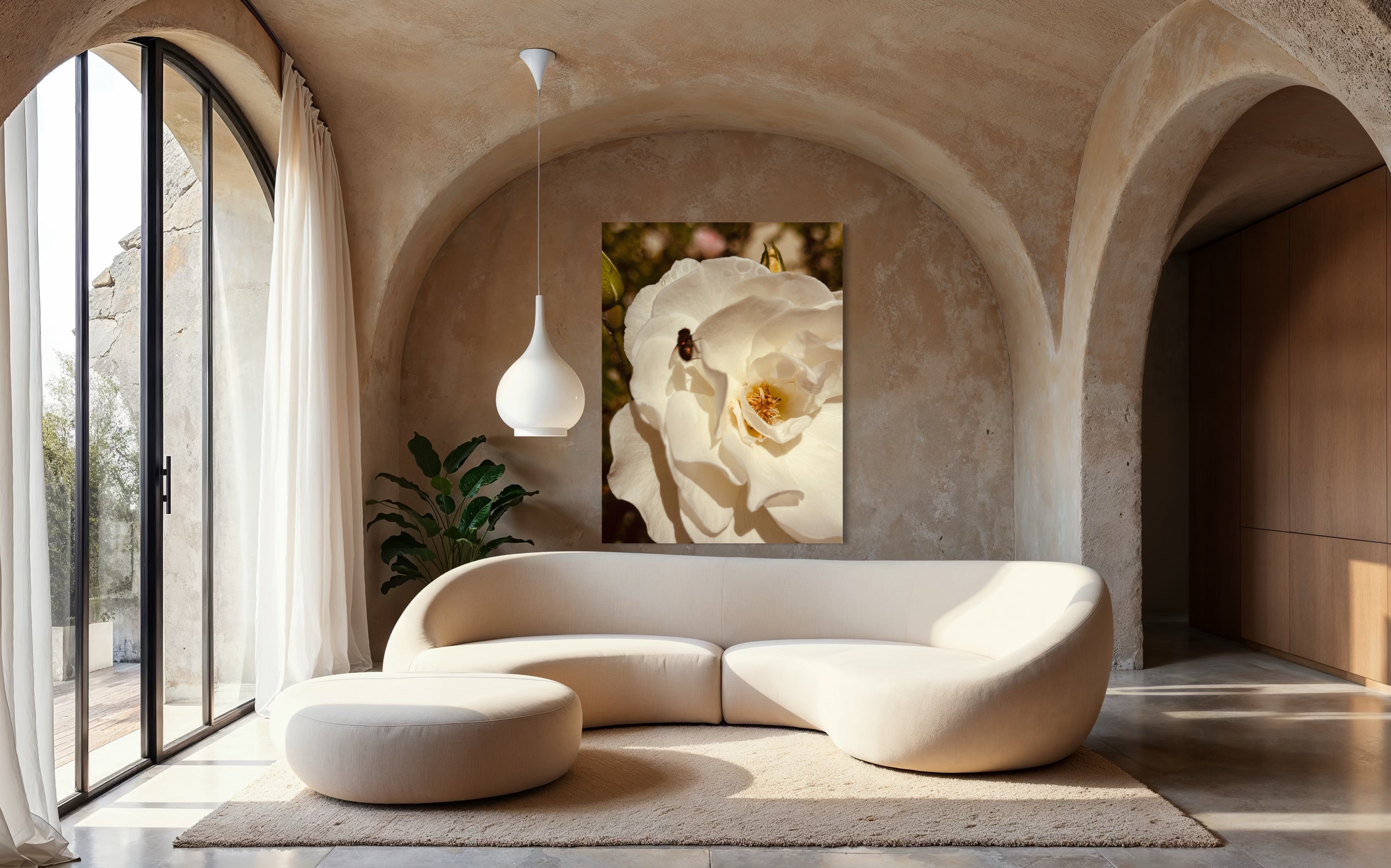 White rose artwork with a small fly showcased above a sculptural cream sofa in an organic, earth-toned interior.