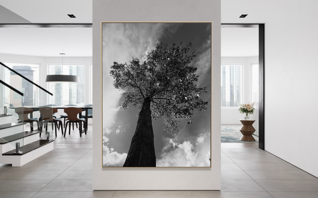 Monochrome tree artwork showcased in a bright contemporary room overlooking an urban skyline.