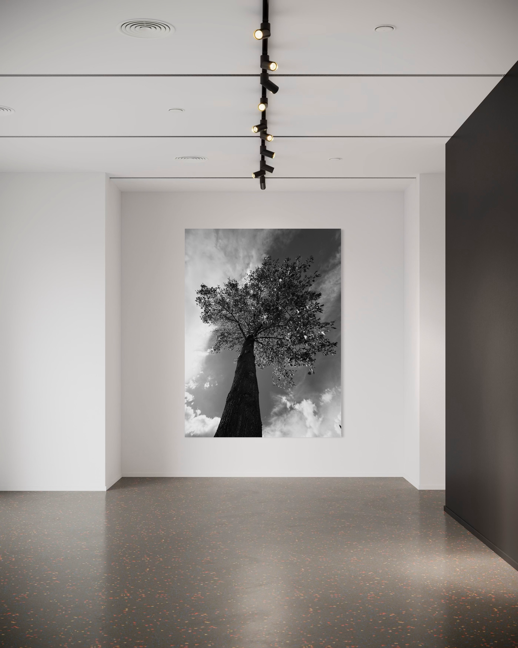 Tall black-and-white tree artwork illuminated against a clean gallery-style white wall.